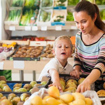 Mother and young son pick out fruit in a market